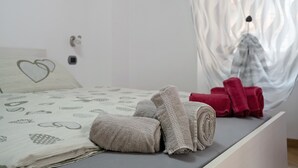A neatly made bed with rolled towels, a heart-patterned pillow, and a window with sheer curtains. - Apartment "Casa Picchio" with Mountain View and Balcony (Rabbi)
