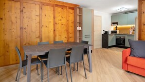 A compact living space with a dining area, kitchenette, and a sofa. - Apartment "Casa Picchio" with Mountain View and Balcony (Rabbi)