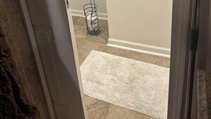 A hallway with a white door, a white rug, and a water dispenser on the floor.