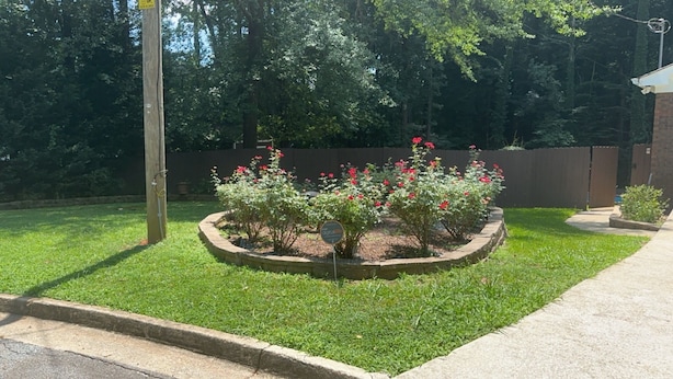 A landscaped garden with a circular flower bed, a wooden fence, and a paved walkway.