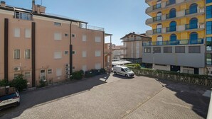 A residential street with multi-story buildings, a parked white van, and a car. - Apartment 'Residence International' with Private Terrace, Balcony and Air Conditioning (Lido di Jesolo)