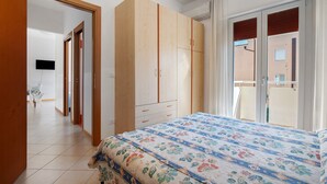 A bedroom with a bed, wardrobe, and a balcony. - Apartment 'Residence International' with Private Terrace, Balcony and Air Conditioning (Lido di Jesolo)