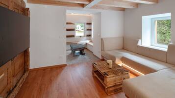 Habitació moderna amb terra de fusta, un sofà, una televisió i una finestra.