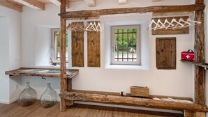 Una habitación rústica con un banco de madera, dos jarrones de vidrio, un botiquín de primeros auxilios rojo y vigas de madera.