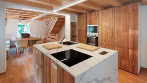 Una cocina moderna con armarios de madera, una isla central con placa de cocción por inducción negra y un horno empotrado.