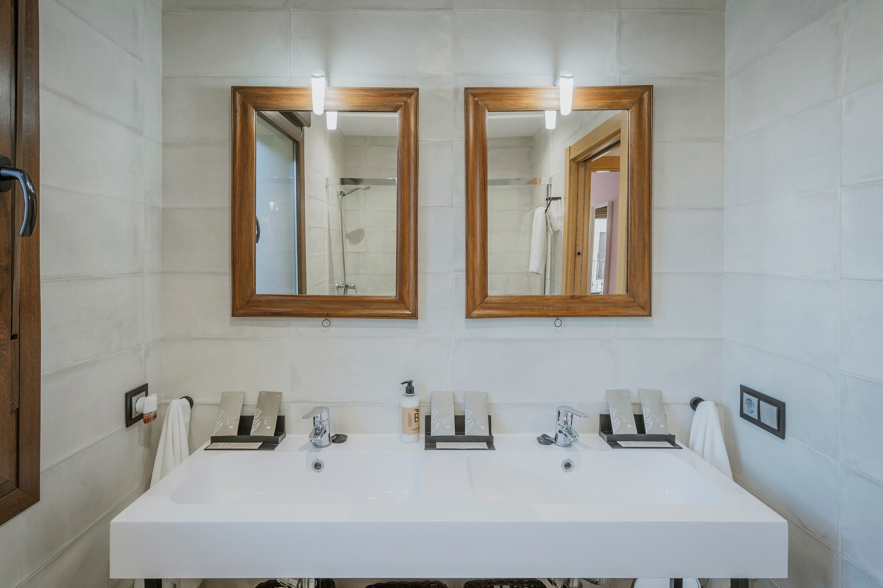 A bathroom with two mirrors, a white sink, and a shower.