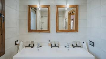 A bathroom with two mirrors, a white sink, and a shower.