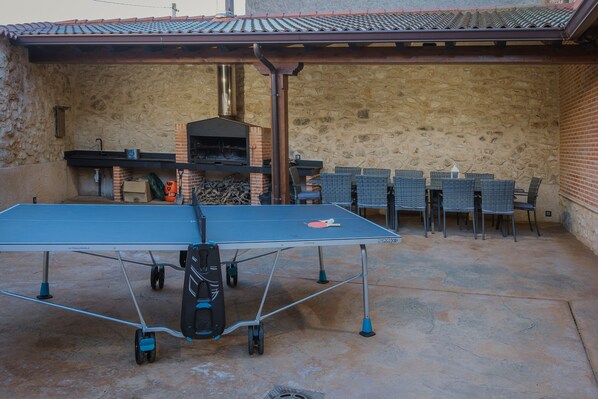 A ping pong table in an outdoor patio area with a stone wall and a brick chimney. - Country House 'La Olma' with Private Terrace, Balcony and Wi-Fi (Campillo de Aranda)