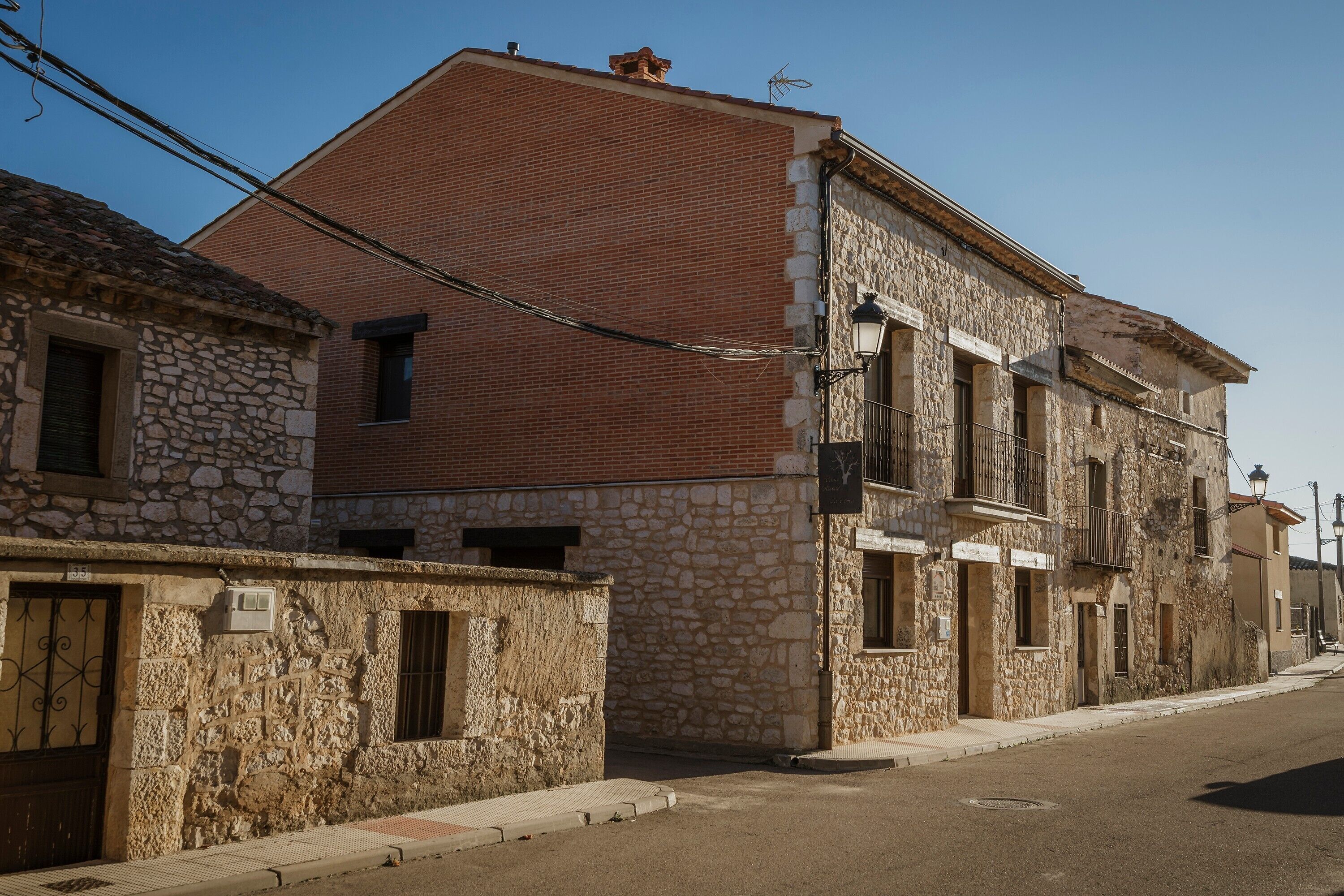 Una calle con edificios de piedra, cielo despejado y una línea eléctrica visible.