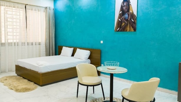 Ein Schlafzimmer mit einem Bett, zwei Stühlen, einem kleinen Tisch und einem Bild an der Wand.