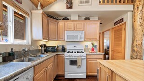 Una cucina con mobili in legno, un forno a microonde, un fornello e un lavandino.