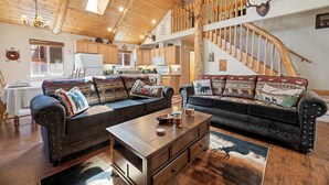 Un'ampia zona giorno con soffitto in legno, un tavolo da pranzo e due divani con cuscini decorati.