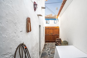 A narrow alleyway with a white wall, a wooden door, and a table with a white tablecloth. - Holiday Home 'Casa Do Pelourinho' with Private Terrace and Wi-Fi (Avis)