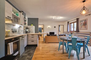 Una cocina moderna con electrodomésticos integrados, un comedor con mesa y sillas, y una sala de estar con sofá.