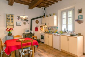 A kitchen with a dining table, chairs, a stove, and a sink.