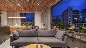 Een moderne woonkamer met een zwart marmeren keuken eiland, een grijze bank en een houten eettafel.
