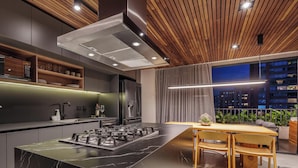 Een moderne keuken met een marmeren eiland, inbouwapparatuur en een eethoek met een houten tafel en stoelen.