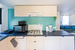Une cuisine compacte équipée d’une cuisinière à gaz, d’un four à micro-ondes et d’une machine à café.