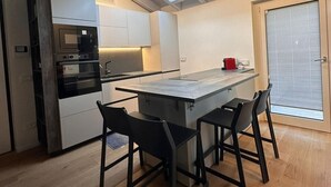 Una cocina moderna con tragaluz, horno empotrado e isla central con taburetes de bar.