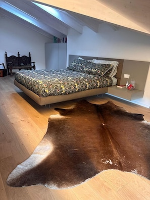 Une chambre à coucher avec un lit, une table de chevet, un banc en bois et une grande moquette en fourrure.