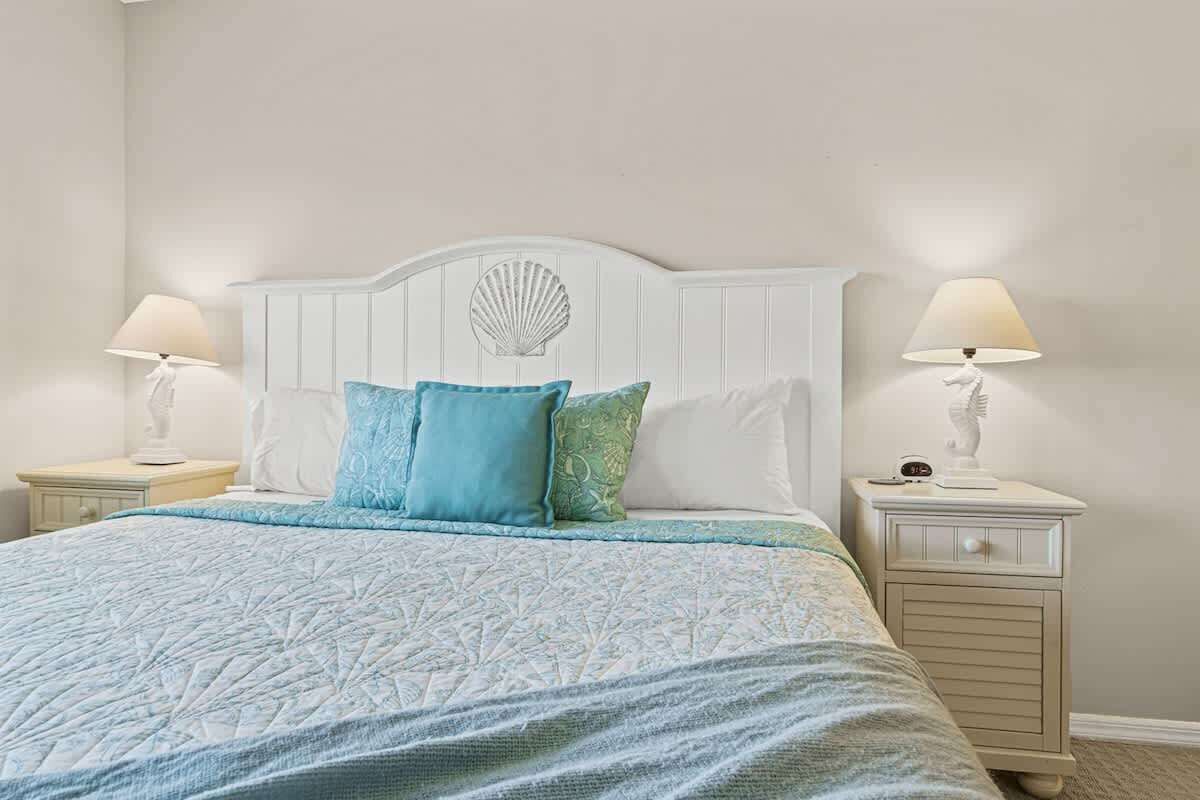 A bed with a white headboard, two bedside tables, and a lamp on each side.