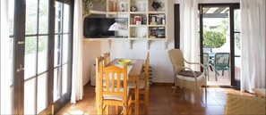 Un coin repas comprenant une table, des chaises, un téléviseur et une bibliothèque.