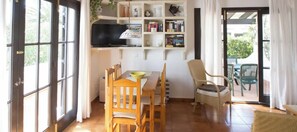 A dining area with a table, chairs, a television, and a bookshelf.