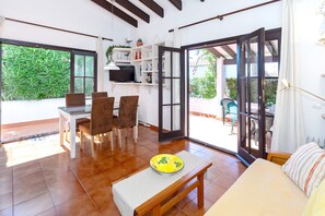 Un'ampia zona giorno con tavolo, sedie, divano e una panca. Una porta vetrata scorrevole conduce a un patio esterno.