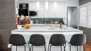 A modern kitchen with a central island, bar stools, a microwave, and pendant lights.