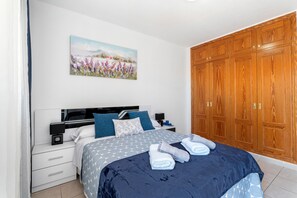 Une chambre à coucher comprenant un lit, une table de chevet, une commode, une armoire et un tableau accroché au mur.