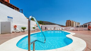 A swimming pool with a metal ladder, lounge chairs, and a lifebuoy.