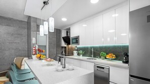 A modern kitchen with a large island, stainless steel appliances, and a marble backsplash.