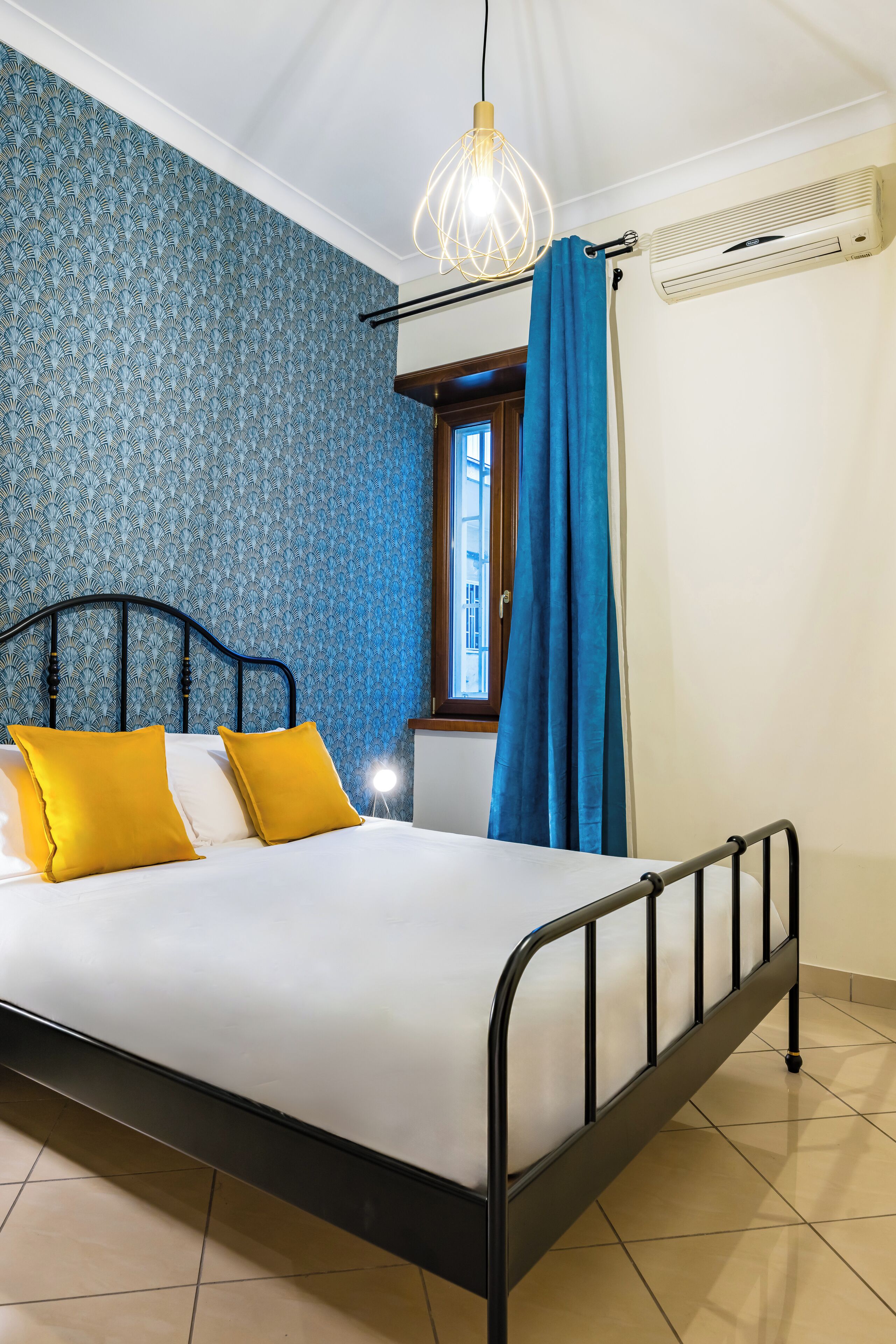 A bed with a metal frame, white bedding, and two yellow pillows.