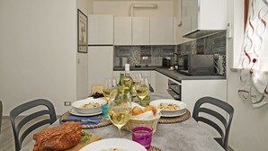 Une cuisine moderne avec des meubles blancs, un four à micro-ondes et une table à manger dressée avec des assiettes, des verres et une bouteille de vin.