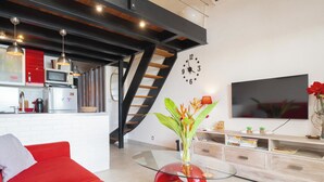 A modern living space with a red sofa, a glass coffee table, a kitchen area with a microwave, and a staircase. - Honoré apartment with views of the marina and golf course 2mn from beaches (Saint-François)