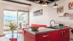 A modern kitchen with red cabinets, a glass island, and a view of the outdoors. - Honoré apartment with views of the marina and golf course 2mn from beaches (Saint-François)