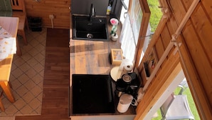 A compact kitchen with a sink, stove, and dining area. - Cozy I Log cabin in the Bavarian Forest I National Park (Neureichenau)