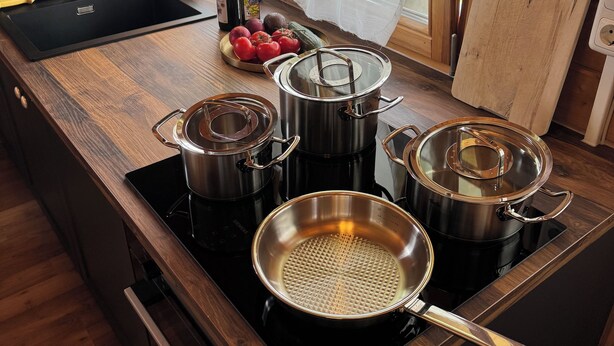 A kitchen with a black sink, wooden countertop, and stainless steel pots. - Cozy I Log cabin in the Bavarian Forest I National Park (Neureichenau)