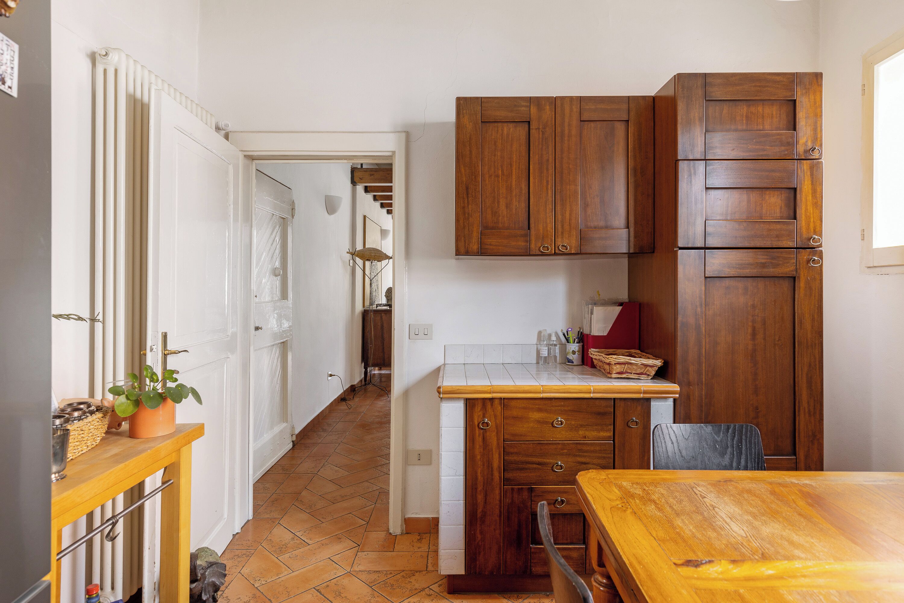 A kitchen with wooden cabinets, a tiled backsplash, and a wooden dining table.