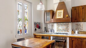 Une cuisine avec des meubles de rangement en bois, une cuisinière et une table à manger avec des chaises.