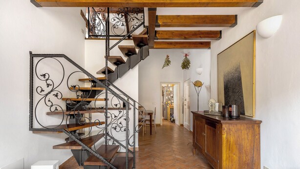 Un vaste espace de vie agrémenté d’un escalier en bois et d’un grand tableau mural.