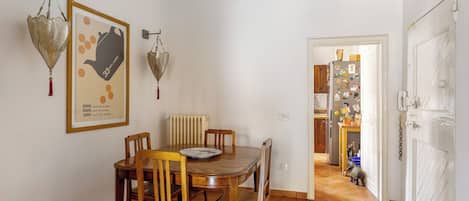 A dining area with a wooden table and chairs, a radiator, and a door leading to a kitchen.