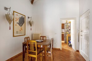 A dining area with a wooden table and chairs, a radiator, and a door leading to a kitchen. - Country Style House in Bologna by Wonderful Italy (Bologna)
