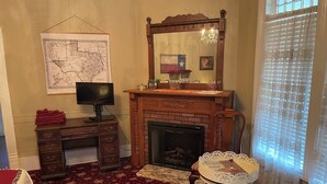 A room with a fireplace, a desk with a computer, a map on the wall, and a window with blinds. - Irishette (Dublin)