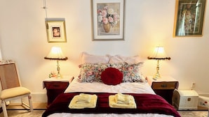 A neatly made bed with a red pillow, two bedside lamps, a chair, and a framed picture on the wall. - Irishette (Dublin)