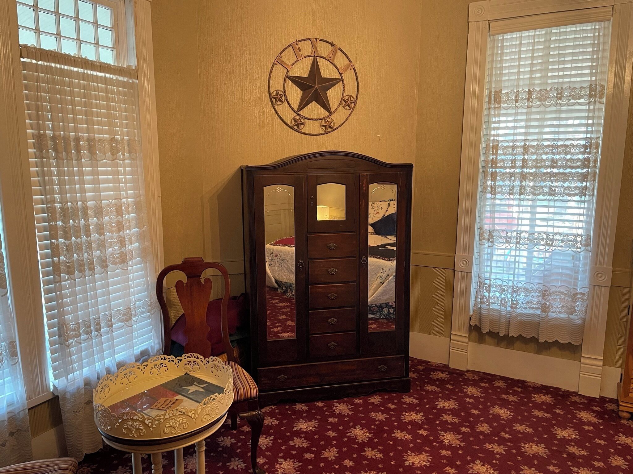 A room with a wooden cabinet, a small table with a decorative top, and a wall clock with a star design.
