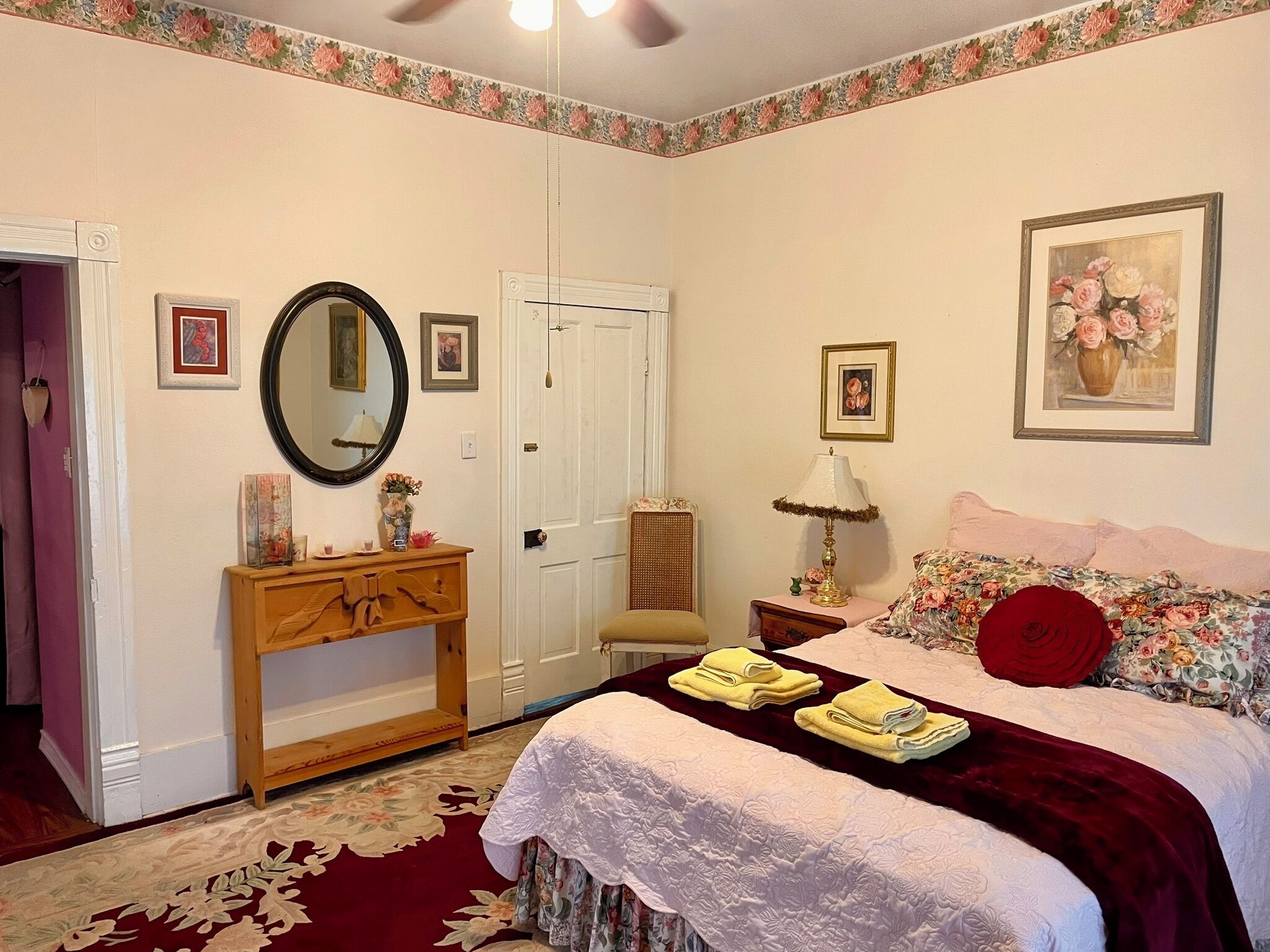 A bedroom with a bed, a dresser, a mirror, a door, and a painting on the wall.