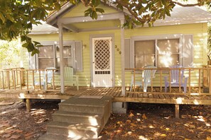A yellow house with a porch, two white chairs, and a wooden bench. - Beaufort Harbour Suites East Lodge (Beaufort)