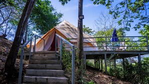 A tented accommodation with a staircase leading to a deck area. - Guanaglamp (Tamarindo)