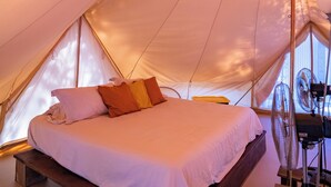 A tent with a bed, a fan, and a small table. - Guanaglamp (Tamarindo)